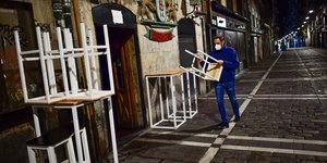 Ανδρας μαζεύει καρέκλες σε πεζόδρομο στην Ισπανία