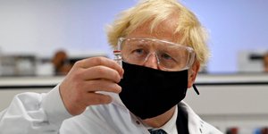 Ο πρωθυπουργός της Βρετανίας, Μπόρις Τζόνσον περιεργάζεται φιαλίδιο με εμβόλιο κατά του κορωνοϊού