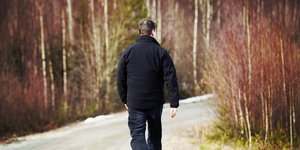 Άνδρας περπατά μόνος σε δρόμο με δέντρα 