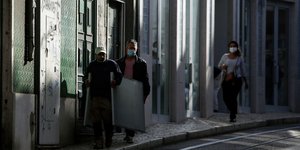 Πορτογάλοι με μάσκες περνούν μπροστά από κλειστά καταστήματα στη Λισαβώνα