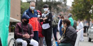Κόσμος στέκεται σε πεζοδρόμιο στην Κολομβία φορώντας μάσκες