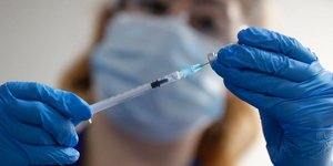 Ειδικός με μάσκα και γάντια κρατά το εμβόλιο της Pfizer