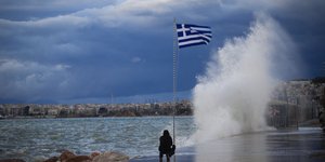 Άνδρας στην παραλία του Φλοίσβου μπροστά στην ελληνική σημαία στις 10 Δεκεμβρίου