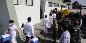 Γιατροί μεταφέρουν εμβόλια υπό το βλέμμα του στρατού