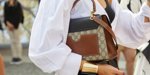 Γυναίκα φορά λευκό πουκάμισο και κρατά τσάντα 