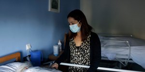 Γυναίκα με μάσκα πάνω από ασθενή σε κρεβάτι νοσοκομείου στην Πορτογαλία
