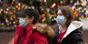 Γυναίκες με μάσκες μπροστά από χριστουγεννιάτικο δέντρο