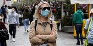 Γυναίκα με μάσκα περπατάει σε δρόμο της Αθήνας