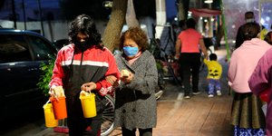 Μεξικανοί περπατούν αγκαζέ φορώντας μάσκες
