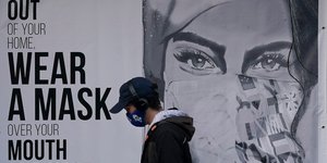 Πεζός περνά από αφίσα για μάσκα