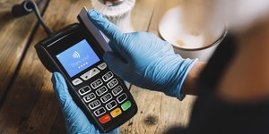 Γυναίκα με γάντια βάζει την κάρτα της σε μηχάνημα POS