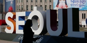 Γυναίκα περνά μπροστά από πινακίδα της Σεούλ