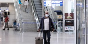 Ταξιδιώτης με μάσκα και βαλίτσα στο αεροδρόμιο