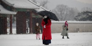 Γυναίκα με μάσκα και ομπρέλα στο χιόνι, στη Νότια Κορέα