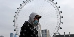 άνδρας με μάσκα μπροστά από το London Eye