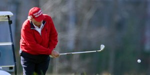 Ο Ντόναλντ Τραμπ με κόκκινο μπουφάν και καπέλο MAGA, παίζει γκολφ