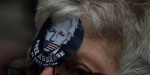 Γυναίκα με κονκάρδα του Τζούλιαν Ασάνζ, φιμωμένου με την αμερικανική σημαία