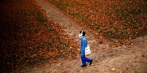 Γυναίκα περπατά σε μονοπάτι ενός πάρκου γεμάτο φύλλα