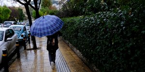 Γυναίκα περπατά στο πεζοδρόμιο με ομπρέλα