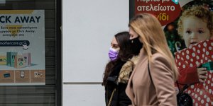 Γυναίκες περπατούν δίπλα σε βιτρίνες