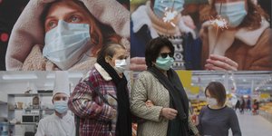Γυναίκες στην Ισπανία με μάσκες περπατούν μπροστά από μία αφίσα