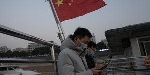 Κινέζοι χαζεύουν το κινητό τους κάτω από την σημαία της χώρας τους