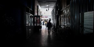 Άνδρας σε στοα με κλειστά καταστήματα λόγω κορωνοϊού