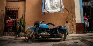 Γυναίκες στην είσοδο του σπιτιού τους στη Κούβα κοιτάζουν μία μηχανή