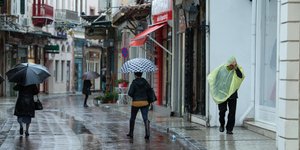 Πεζοί περπατούν στην βροχή σε πεζόδρομο