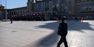 Πεζός μιλά στο κινητό έξω από τον Σιδηροδρομικό σταθμό του Πεκίνου