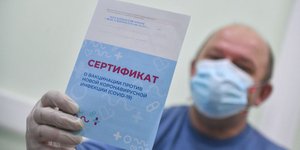 Πολίτης με μάσκα κρατά το πιστοποιητικό για το ρωσικό εμβόλιο