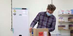 Υπάλληλος τοποθετεί κούτα με εμβόλια