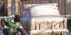 Άνδρας περιεργάζεται το αυτοκίνητό του που έχει καλυφθεί από πάγο στη Βουδαπέστη της Ουγγαρίας