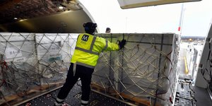 Υπάλληλος ελέγχει κιβώτιο με εμβόλια σε αεροδρόμιο