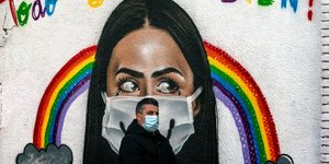 Άνδρας με μάσκα μπροστά από γκράφιτι στην Ισπανία