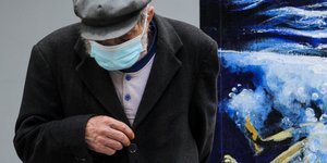 Ηλικιωμένος με μάσκα δίπλα σε γκράφιτι