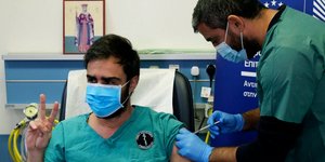 Νοσηλευτής στην Κύπρο κάνει το σήμα της νίκης, όσο του χορηγείται μια δόση του εμβολίου ενάντια στον κορωνοϊό