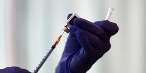 Γάντια κρατούν φιαλίδιο με το εμβόλιο της Pfizer