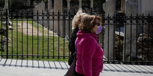 Δυο γυναίκες περπατούν μπροστά από αρχαιολογικό χώρο στην Πλάκα