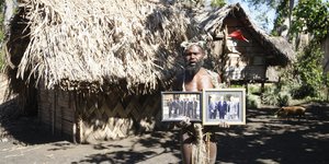 άνδρας από τη φυλή κρατά φωτογραφίες με τον πρίγκιπα Φίλιππο