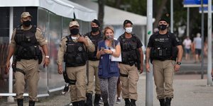 Γυναίκα περπατά μπροστά από αστυνομικούς στη Βραζιλία