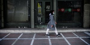 Μια γυναίκα περπατά μπροστά από κλειστό κατάστημα στη Σταδίου