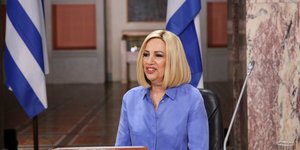 Η Φώφη Γεννηματά με φόντο ελληνικές σημαίες