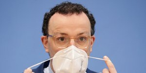 Ο Γερμανός υπουργός Υγείας, Γενς Σπαν, βγάζει τη μάσκα του κατά τη διάρκεια συνέντευξης Τύπου