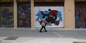 Γυναίκα περπατά σε εμπορικό δρόμο με κλειστά μαγαζιά