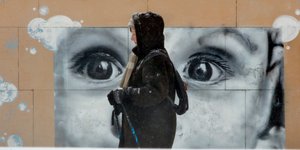 Γυναίκα στην παγωμένη Μόσχα περπατά μπροστά από γκράφιτι με την εικόνα ενός μωρού στη Ρωσία