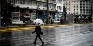 Γυναίκα περπατά με ομπρέλα στον δρόμο