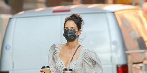 H Kέιτι Χολμς με φόρεμα κρατάει καφέ