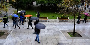Κόσμος περπατά με ομπρέλες