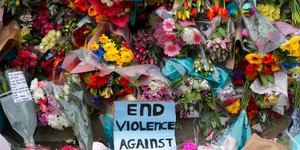 Τελειώστε τη βία κατά των γυναικών γράφει ένα πλακάτ περιτριγυρισμένο από λουλούδια στο Λονδίνο